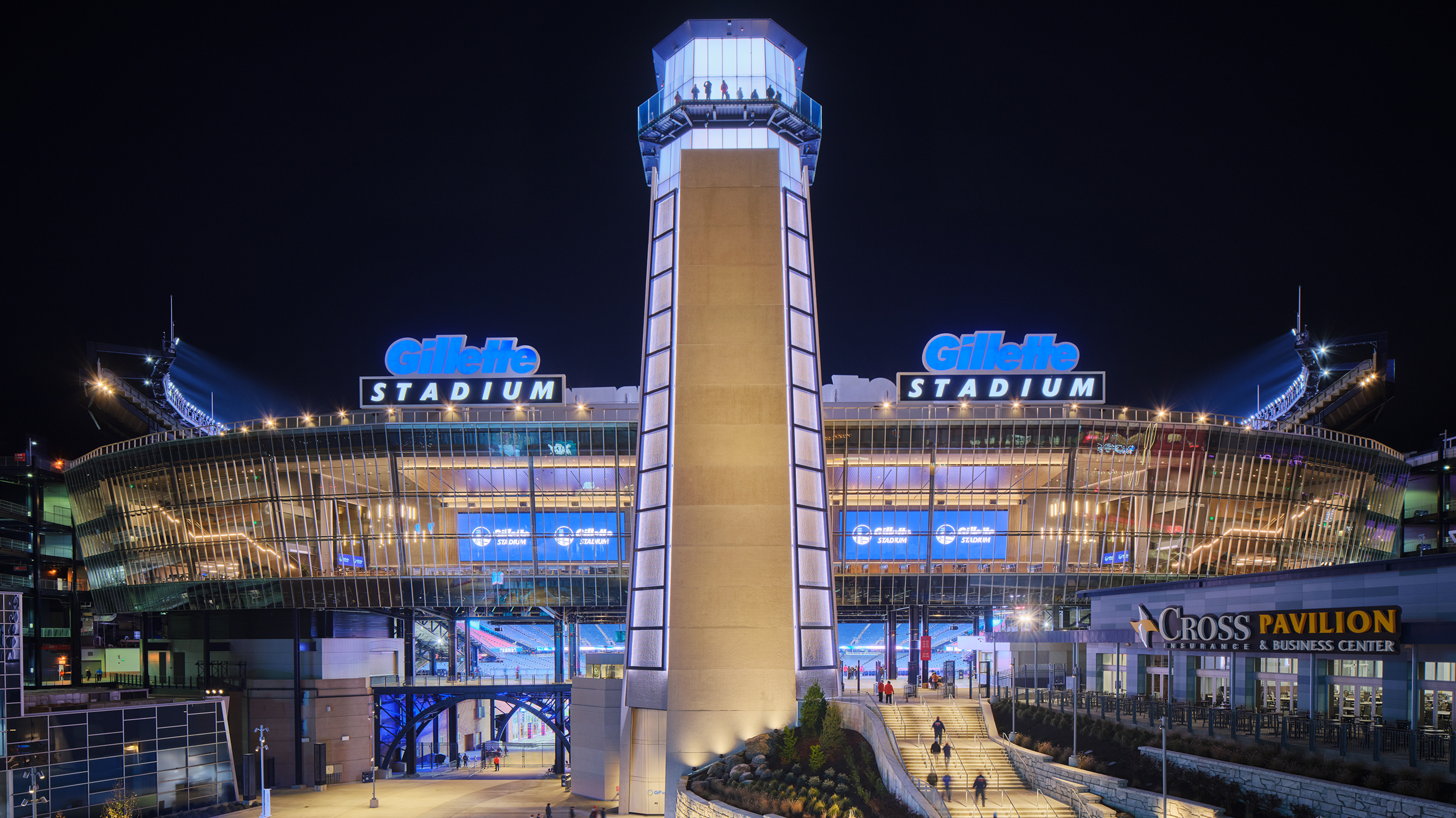 Gillette Stadium Lighthouse lit up at night.