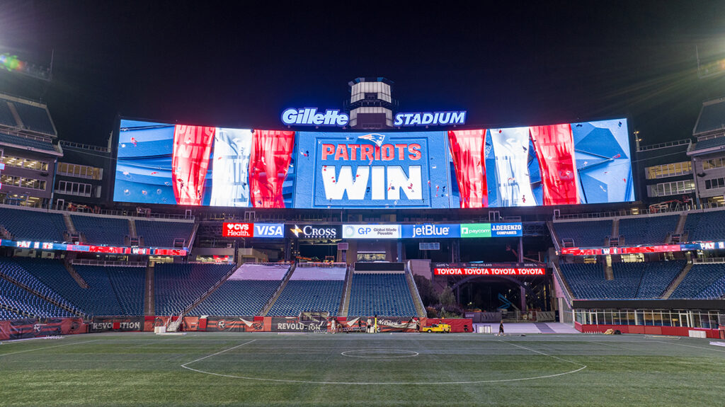 Patriots win graphic on the scoreboard at night. The stadium is empty.