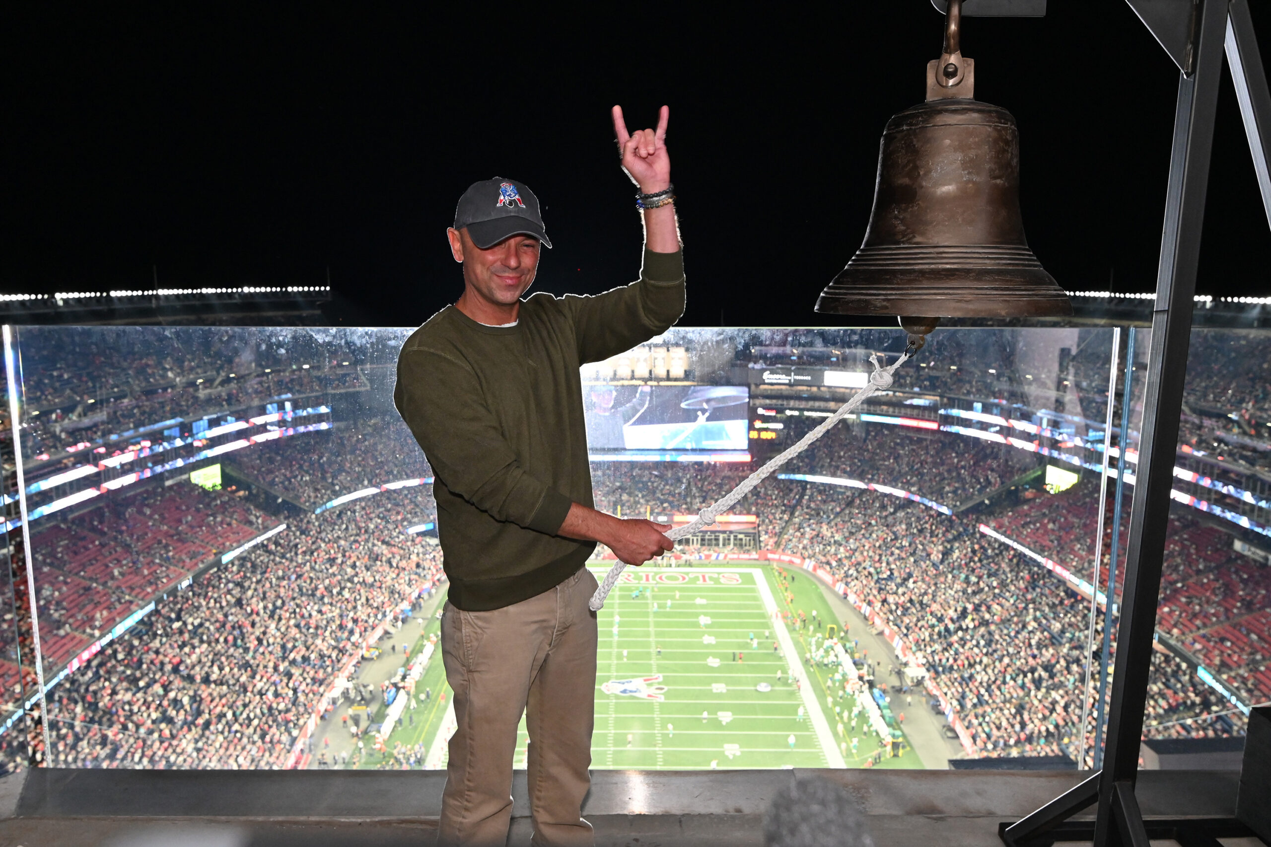 Kenny Chesney ringing the bell and smiling at the camera.