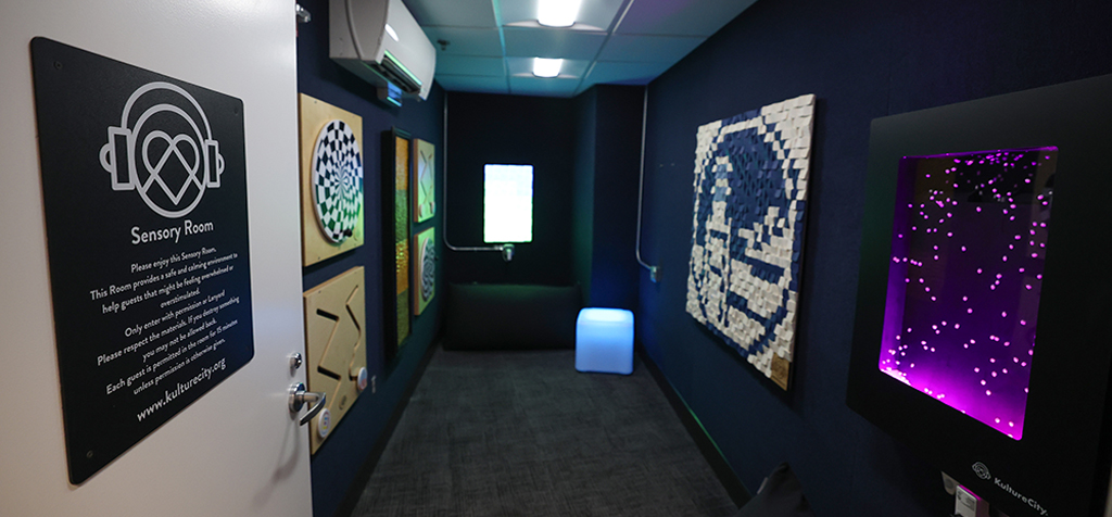 A hall within the Sensory Room with activities and signs on each side of the black walls.